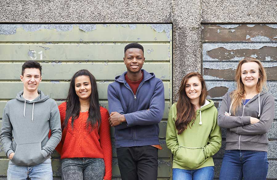 two male teens and three female teens smile because they're helping troubled youth