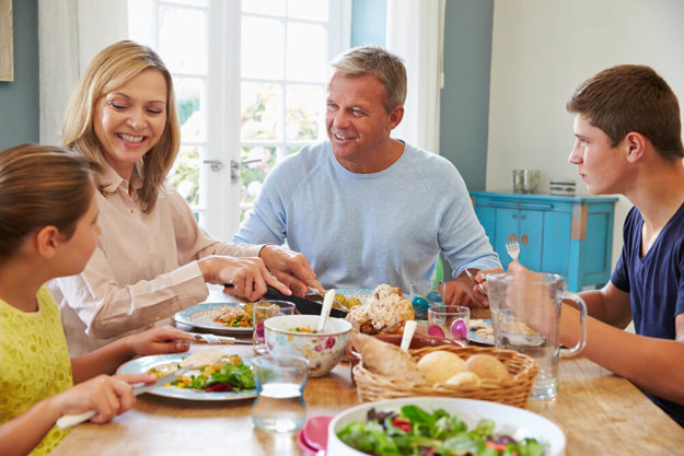 a happy family sits at a table having a family meal