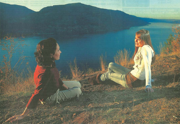 a girl and her mom sit overlooking mountains and water