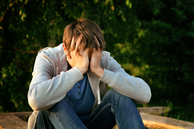 teen boy sitting on ground defining substance abuse