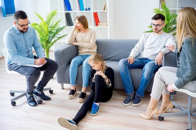 family in a therapist's office participates in family therapy activities on a couch