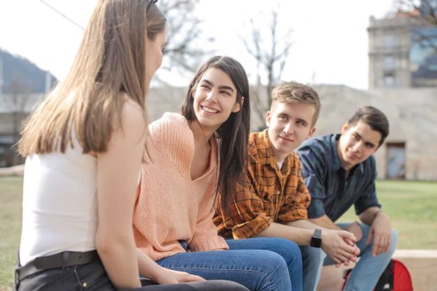 four teens sit outside and talk as they're participating in group therapy activities