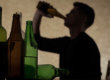 man drinking and surrounded by bottles ready to learn how to stop binge drinking