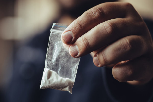 man holds plastic baggie of cocaine while experiencing cocaine abuse symptoms