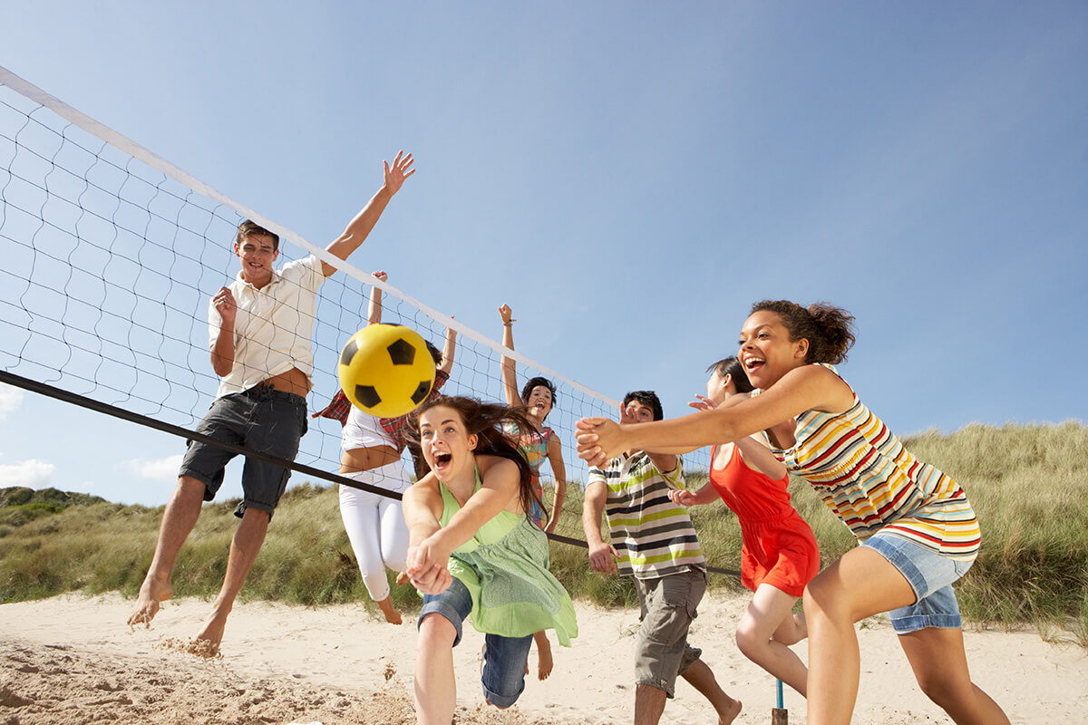  Teenagers play volleyball on the beach.