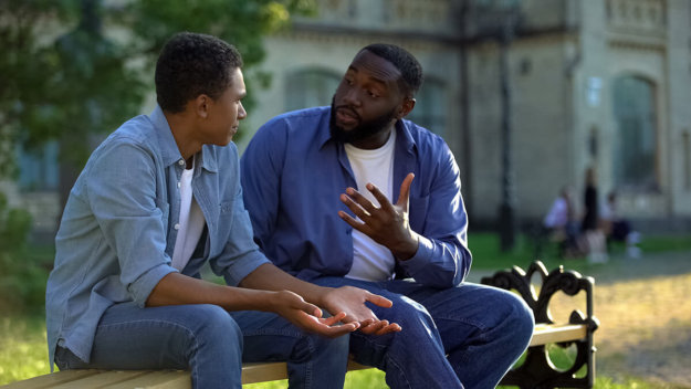 father and son talking on a bench about how to respond to teen attitude