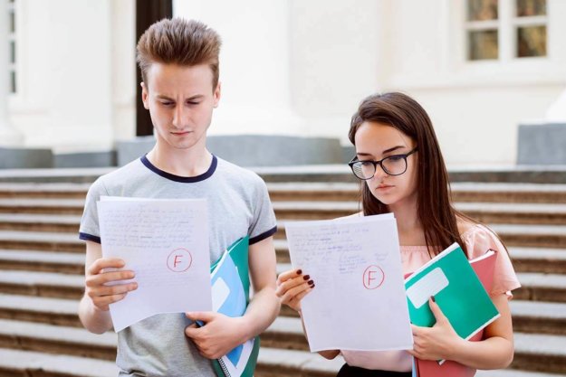 disbelieving teens looking at their papers with poor grades