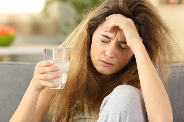 a woman with her hand on her forehead suffering from alcohol dependence symptoms