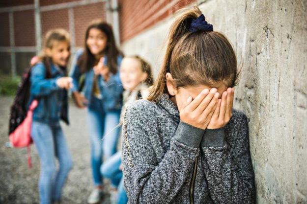 three young girls bully a fourth young girl to the point of tears