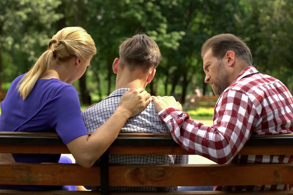 parents have an important and supportive conversation with their teen son at the park