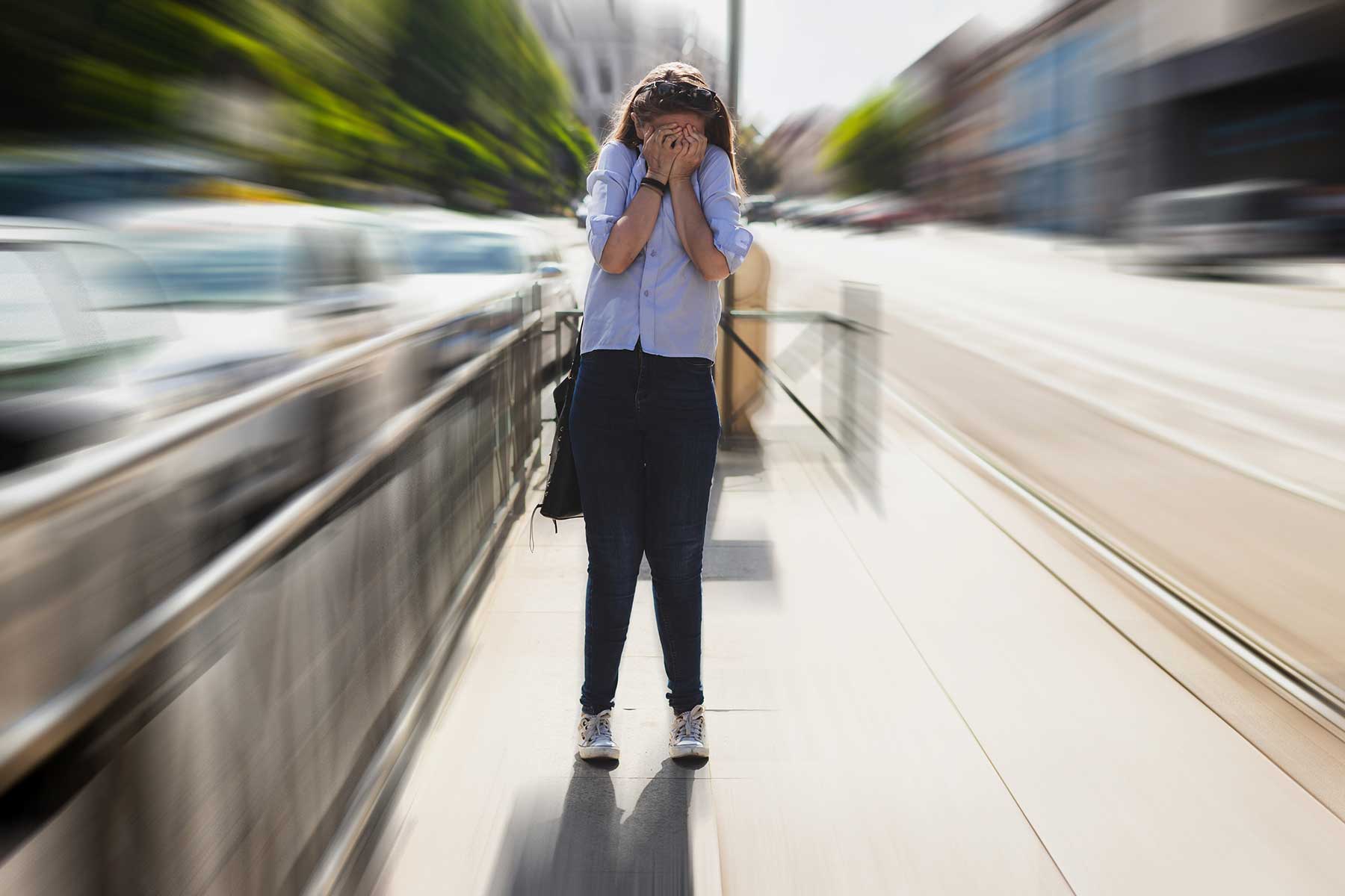 a young woman starts to spiral in an anxiety attack in public on the sidewalk on her way to work