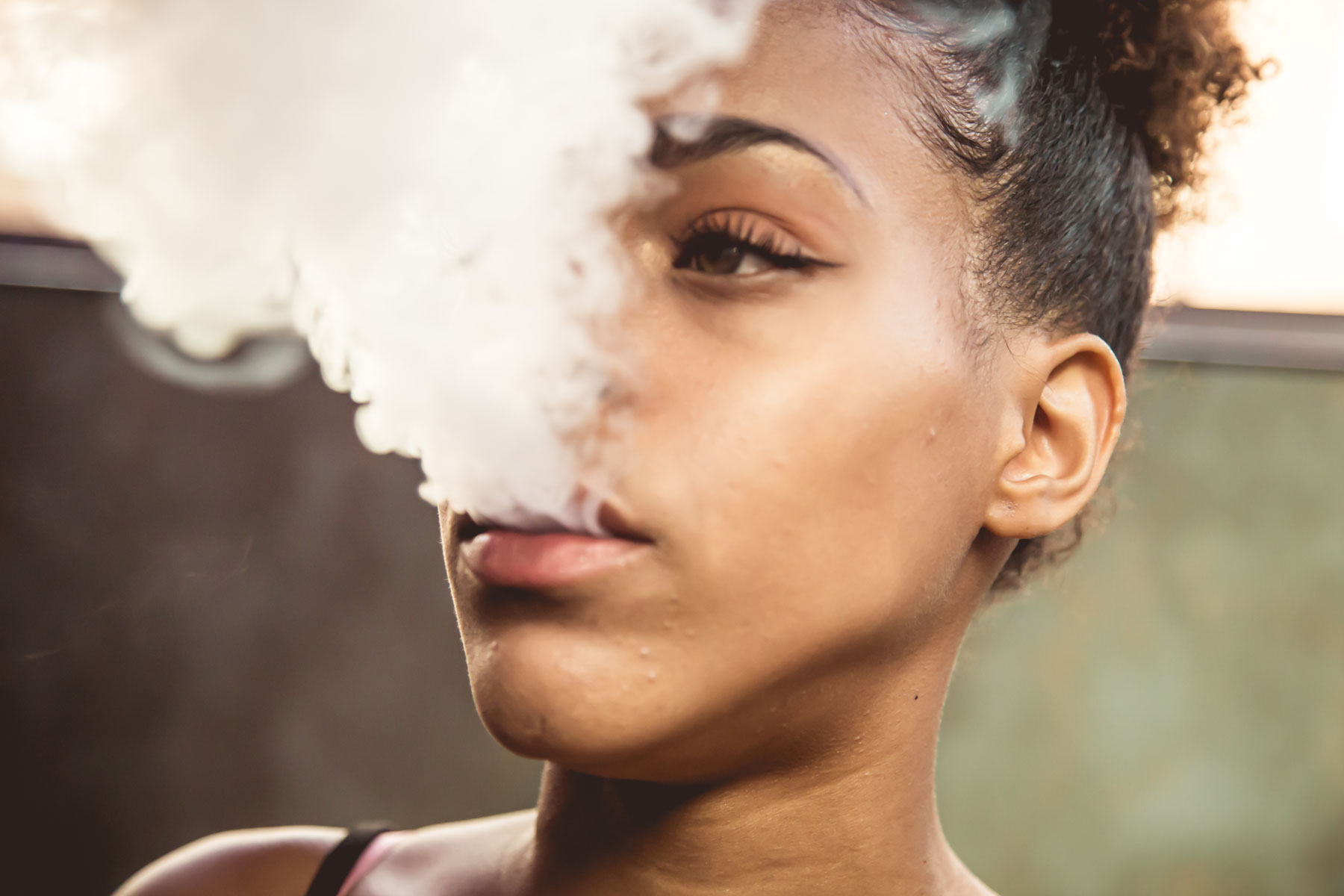 a teen blows out a cloud of cannabis smoke